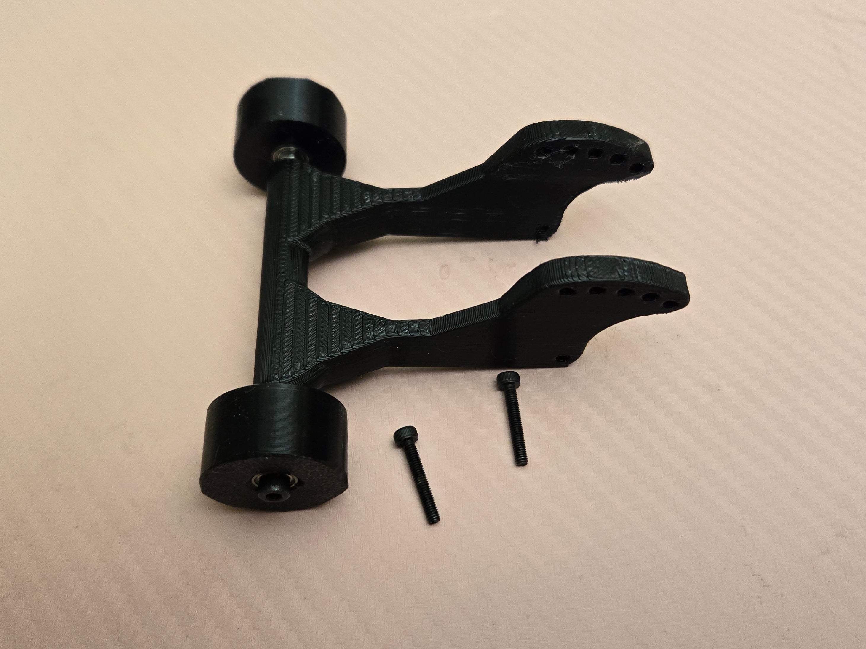 Black mechanical component with screws on a beige surface