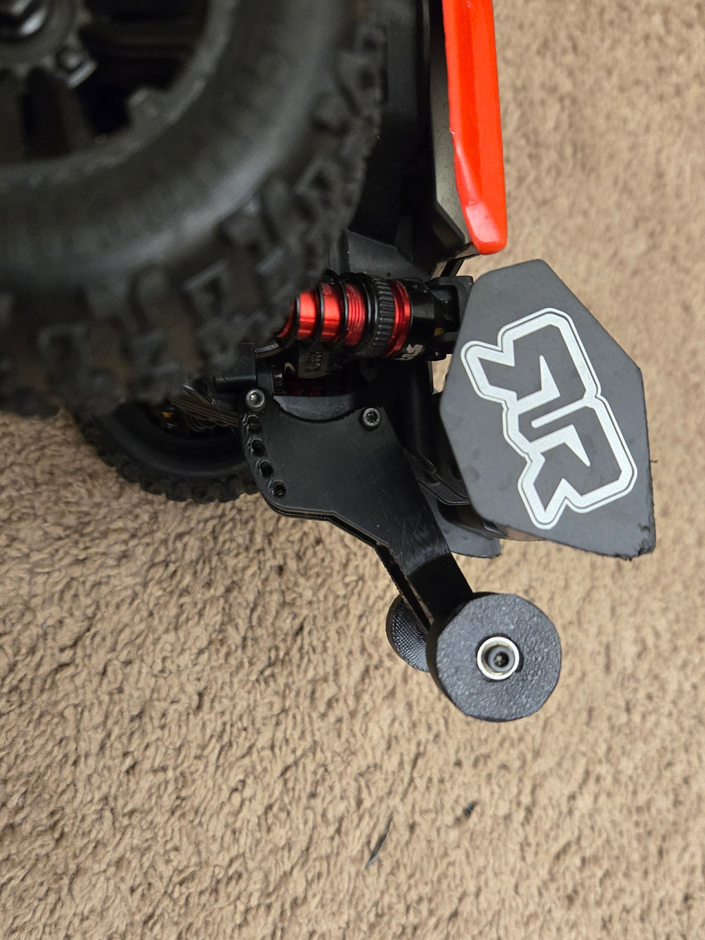 Close-up of a remote control car's suspension system on a carpeted floor